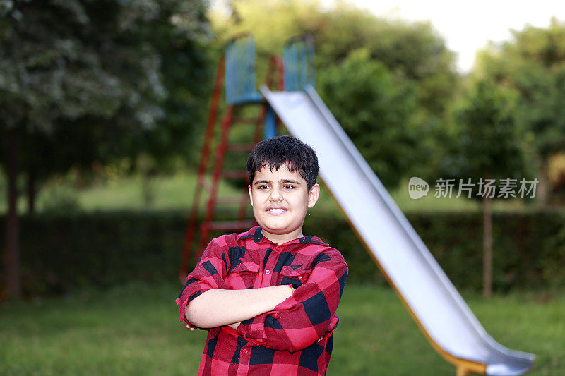Child with toothy smile standing near slide in the park portrait close up
